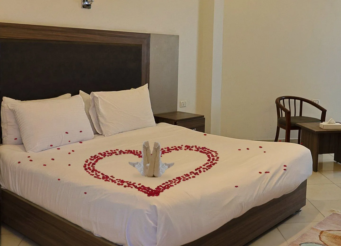 Ein für die Flitterwochen vorbereitetes Doppelzimmer: ein Herz aus roten Rosenblättern und zwei Handtuchschwäne auf dem Bett