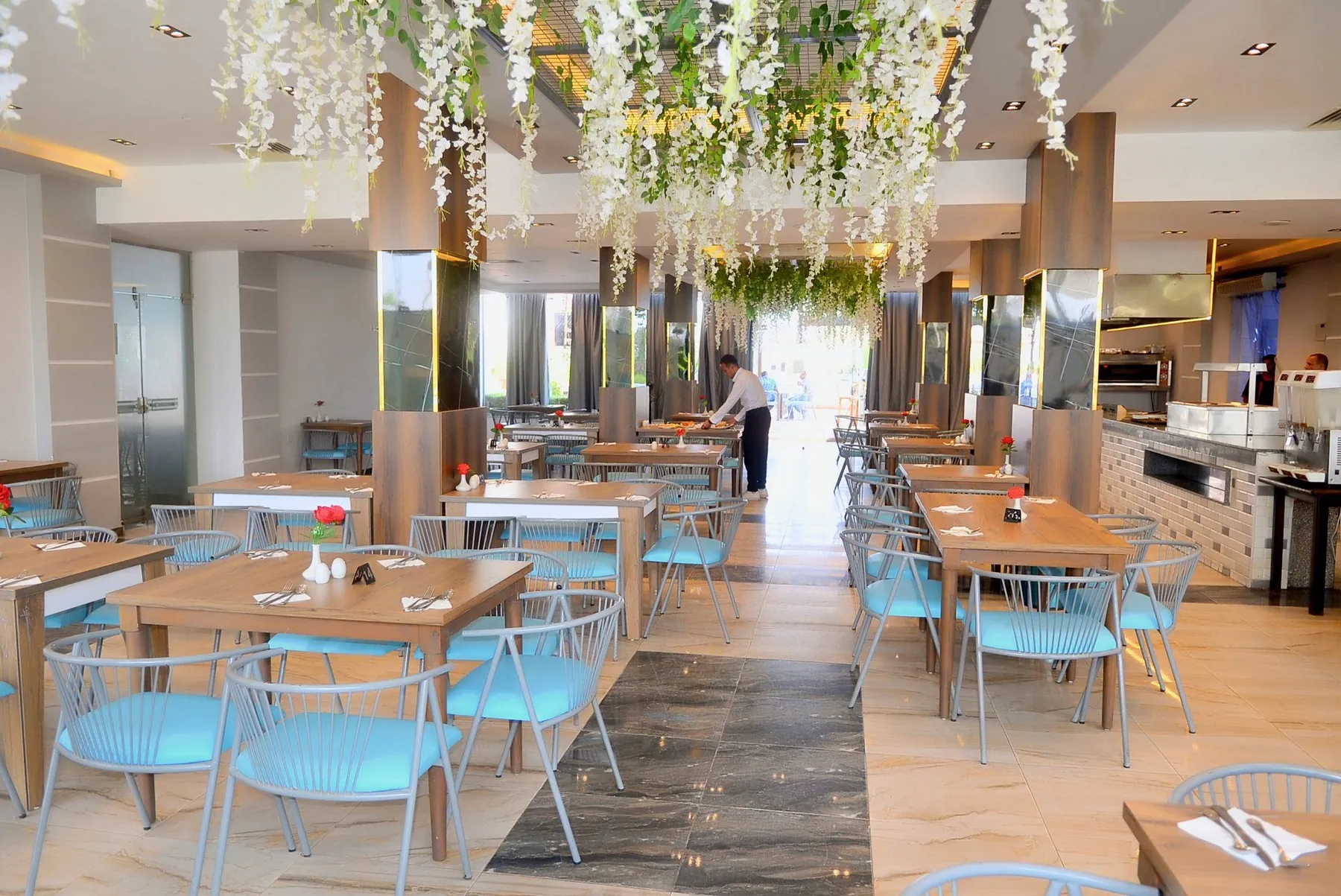 The main restaurant with light-blue chairs and white flowers hanging from the ceiling